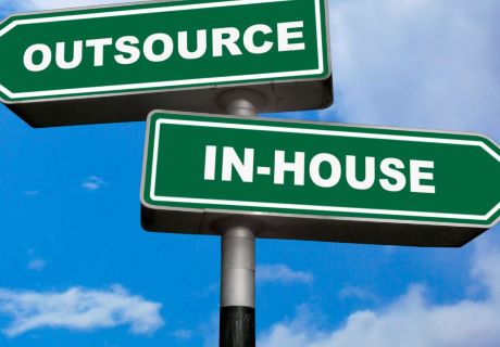 A sign showing direction to outsource to a marketing company or keep things in-house.